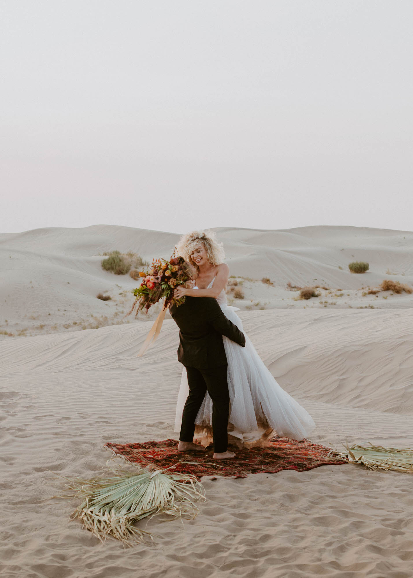 Bride picking up groom to celebrate on their wedding day at the Little Sahara Sand Dunes in Utah.