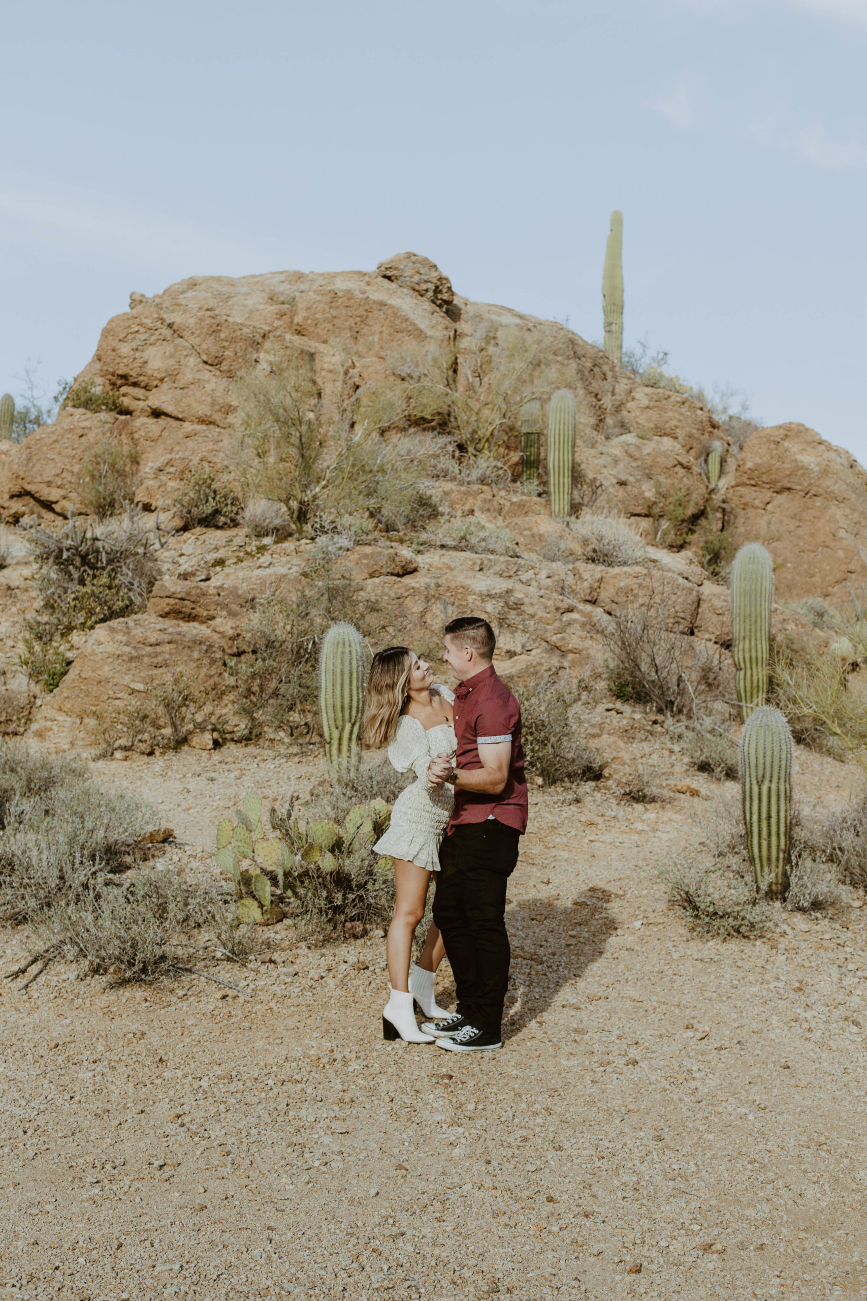 Couple laughing at Gates Pass in Saguaro National Park during their engagement session at golden hour.