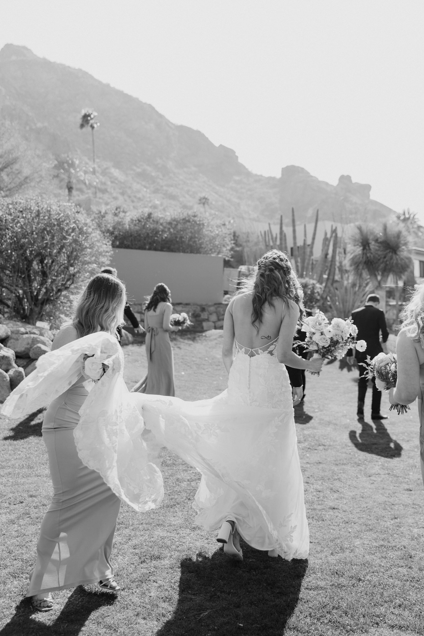 Bridesmaids walking and carrying bride's dress at the Sanctuary Camelback Mountain wedding venue.