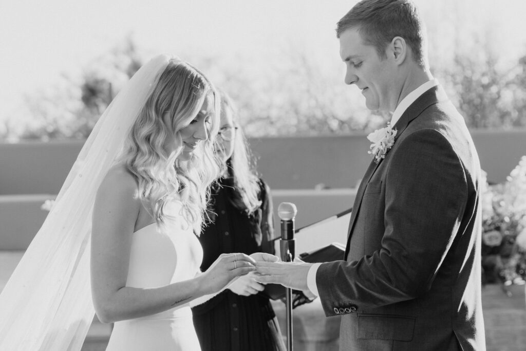Bride placing wedding band on groom's finger at the alter during their wedding ceremony